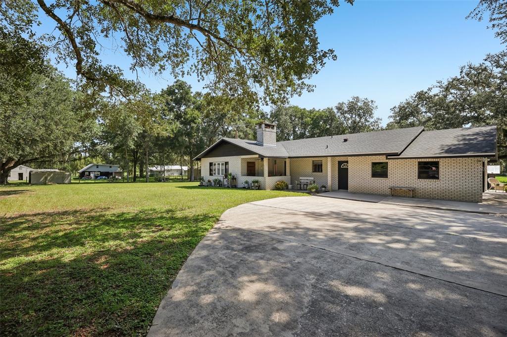 A single-story brick house with a large concrete driveway and a spacious grassy yard — 209 JASPER STREET, BUSHNELL, FL