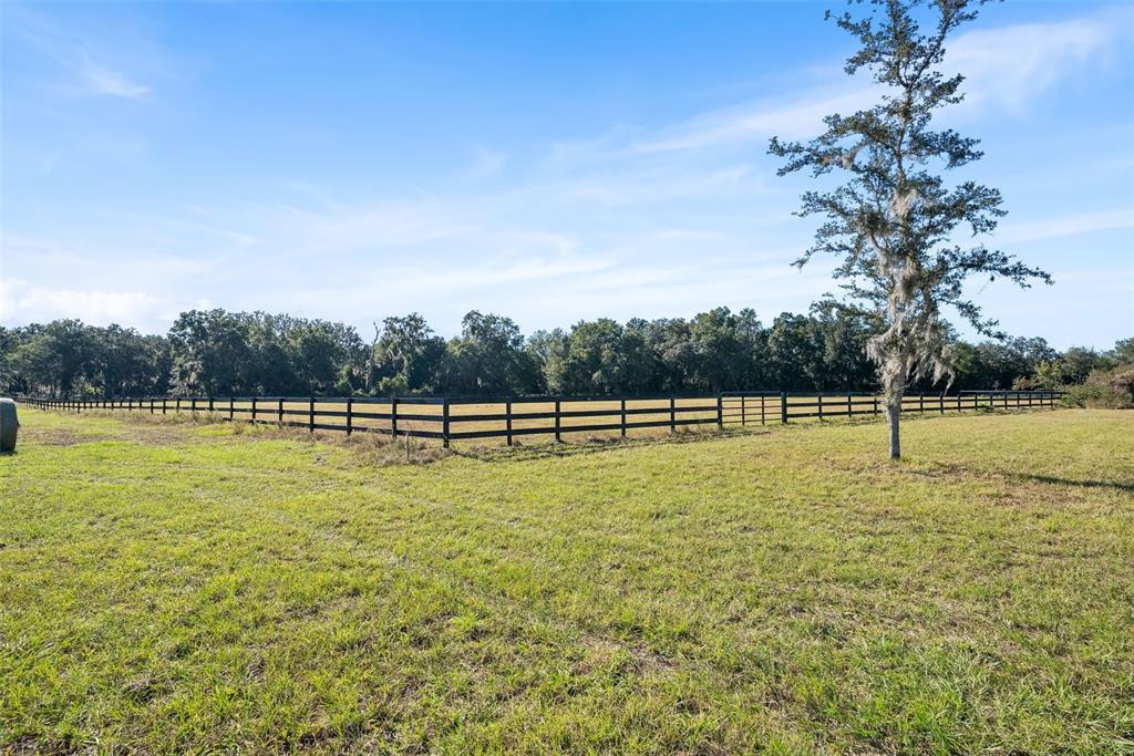 An aerial view shows a cleared sandy building pad on a large, fenced grassy lot — 12793 SW 138TH LOOP, DUNNELLON, FL