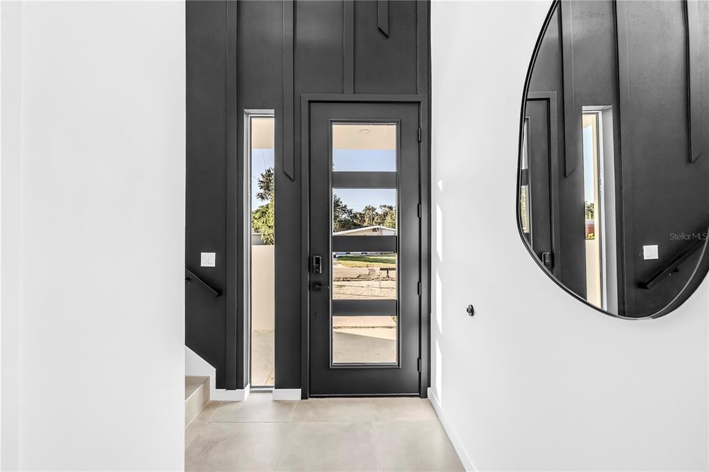 A modern entryway features a black front door with glass panels and a large mirror — 2305 TEMPLE STREET, SARASOTA, FL