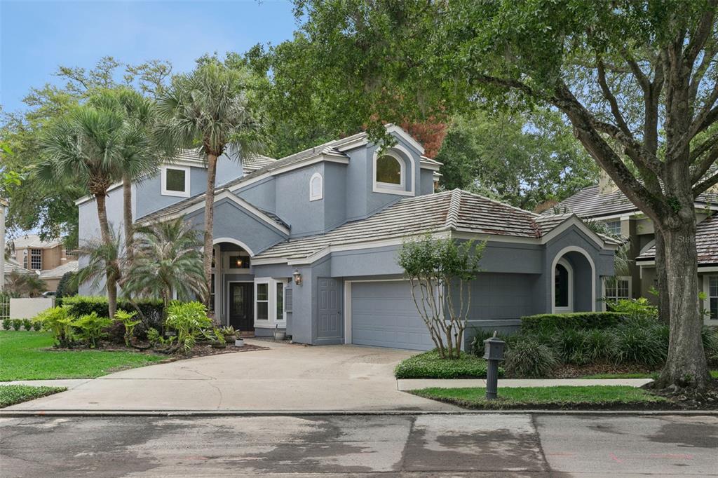 A two-story blue house with a concrete driveway, a two-car garage, and palm trees — 501 DEVON PLACE, LAKE MARY, FL