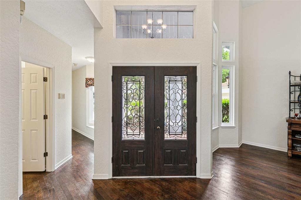 A foyer with dark wood floors, double front doors with decorative glass, and high ceilings — 501 DEVON PLACE, LAKE MARY, FL