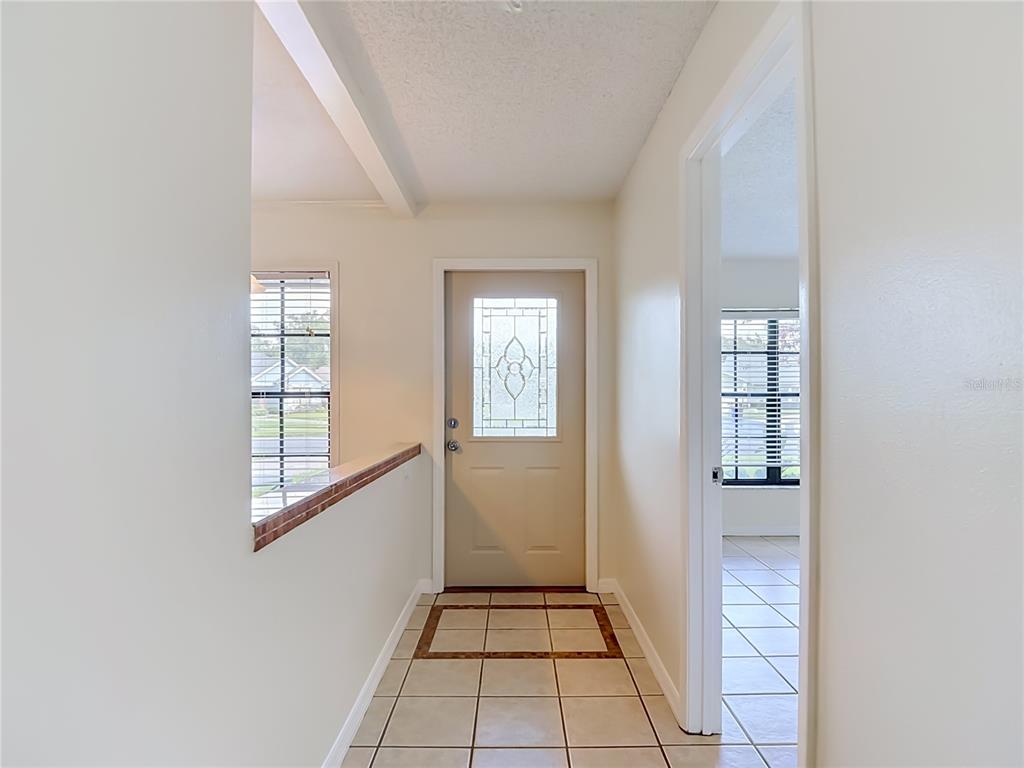 An entryway features a light-colored front door with a decorative glass insert and tiled flooring — 11510 PAMPAS DRIVE, NEW PORT RICHEY, FL