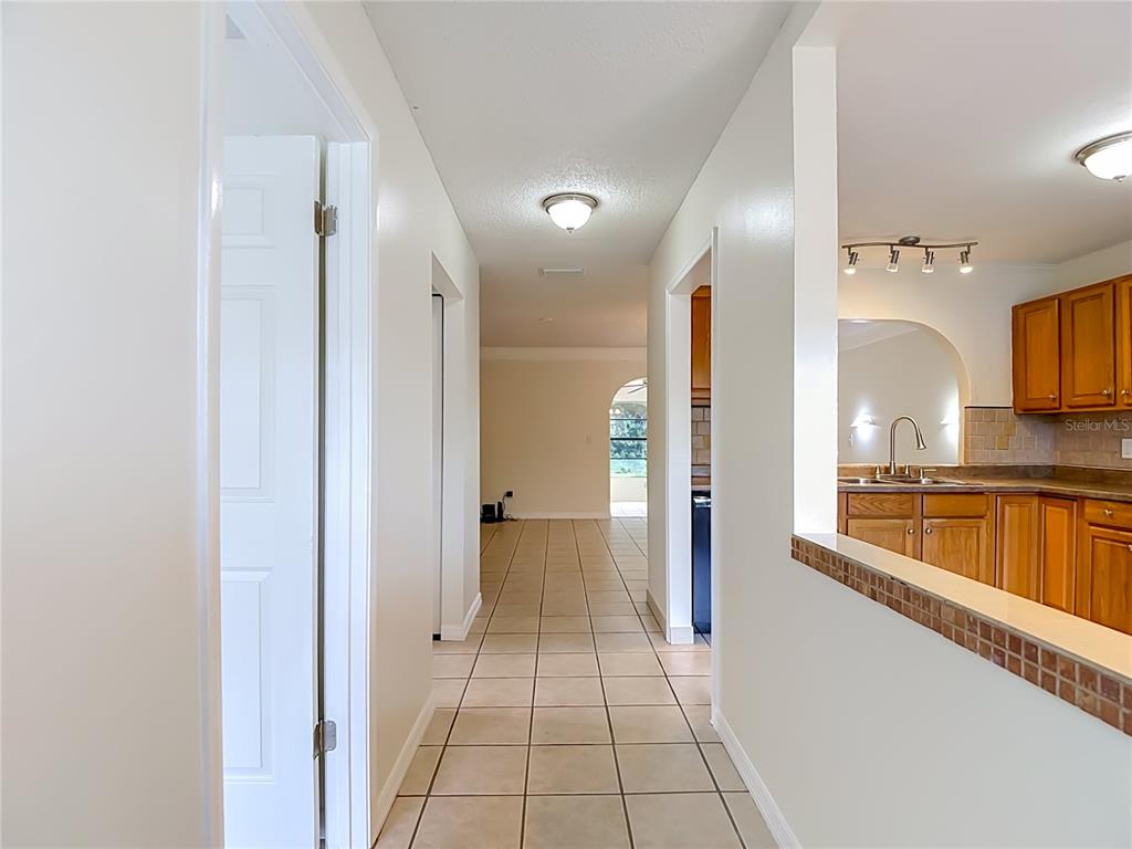 A tiled hallway leads to a living area with a view into a wood-cabinet kitchen — 11510 PAMPAS DRIVE, NEW PORT RICHEY, FL