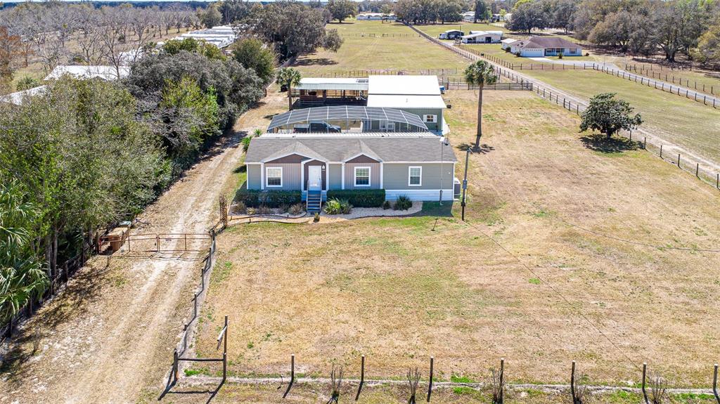 An aerial view shows a single-story house with a screened-in porch on a rural lot — 26444 COUNTY ROAD 44A, EUSTIS, FL