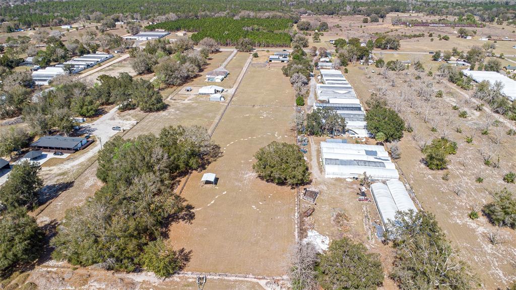 An aerial view shows a long, narrow plot of land with greenhouses and several buildings — 26444 COUNTY ROAD 44A, EUSTIS, FL