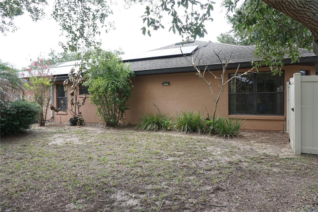 The exterior of a tan stucco house features a shingled roof with solar panels — 4531 TREASURE CAY ROAD, TAVARES, FL