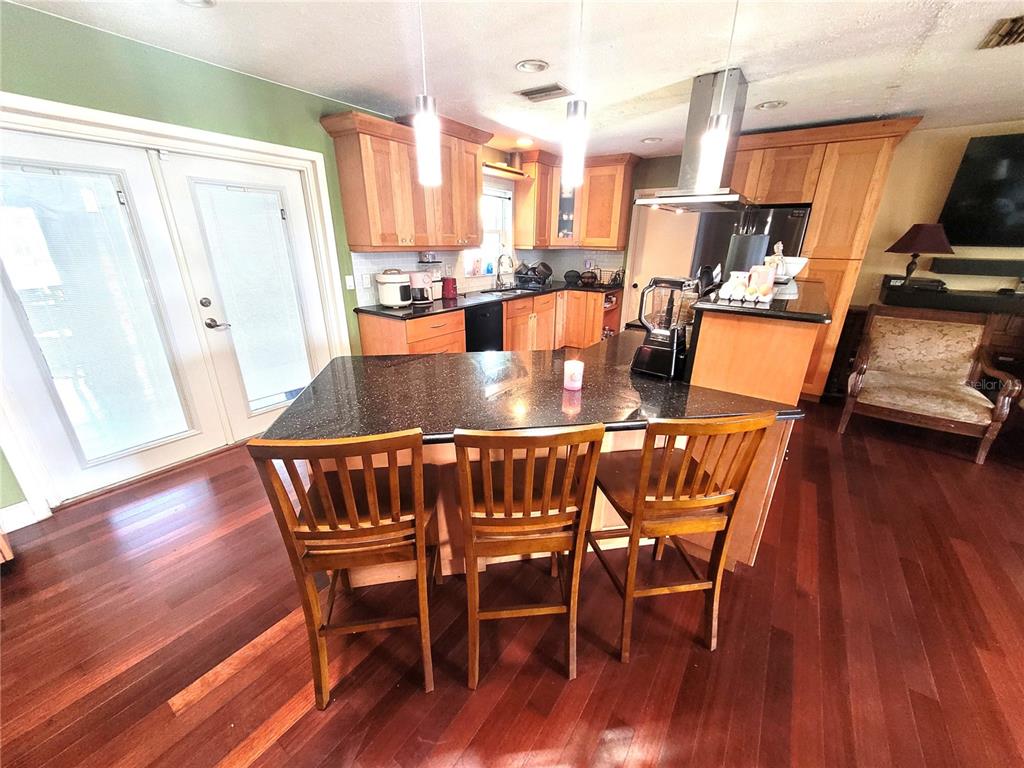 A kitchen features wood cabinets, a black countertop island with seating, and dark hardwood floors — 5203 PRESIDENTIAL STREET, SEFFNER, FL