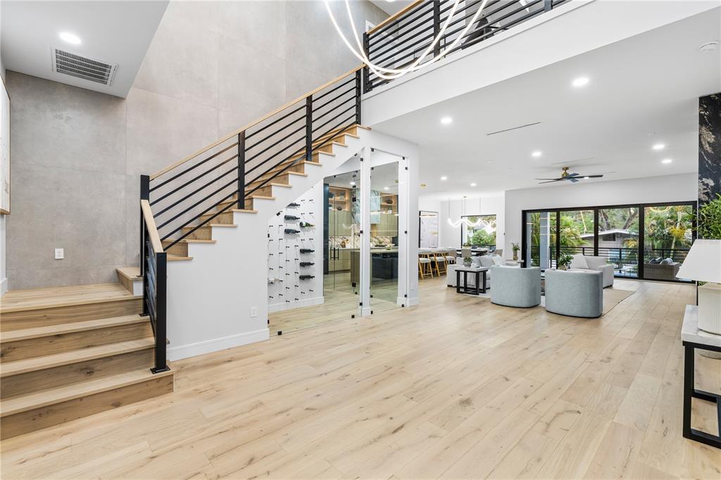 A modern entryway features light wood floors, a black front door, and a glass-enclosed wine cellar — 4709 W ESTRELLA STREET, TAMPA, FL