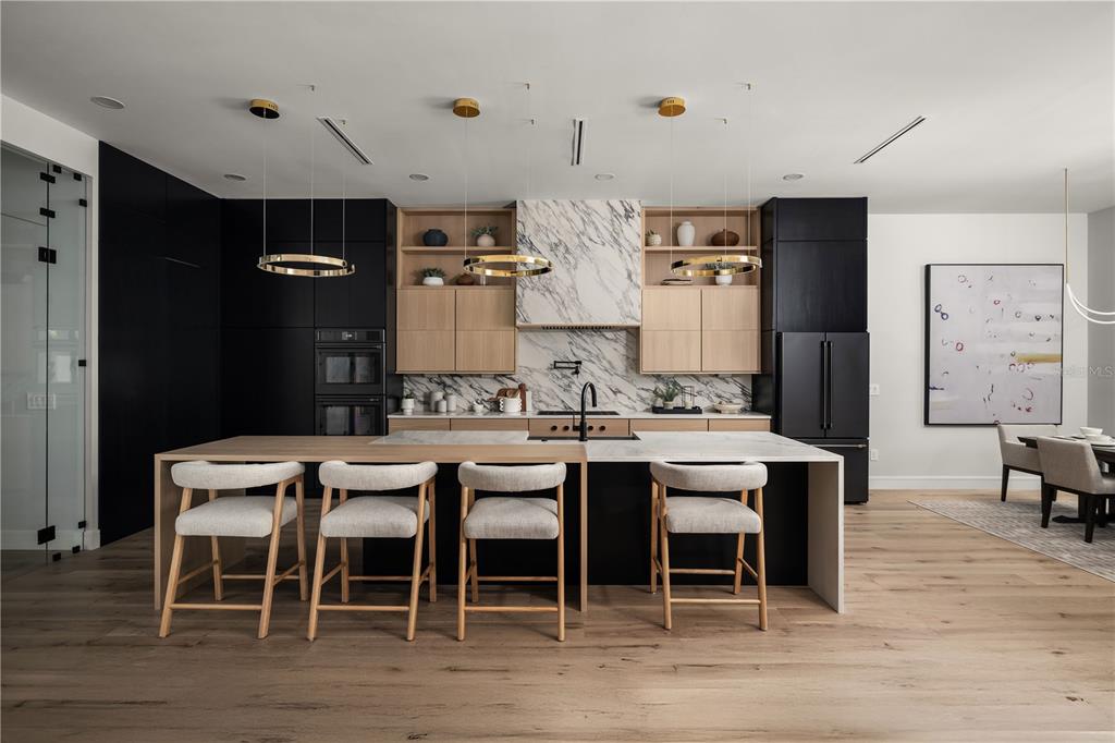 A modern, high-ceilinged living area features a floating staircase, wine display, and a statement chandelier — 4709 W ESTRELLA STREET, TAMPA, FL