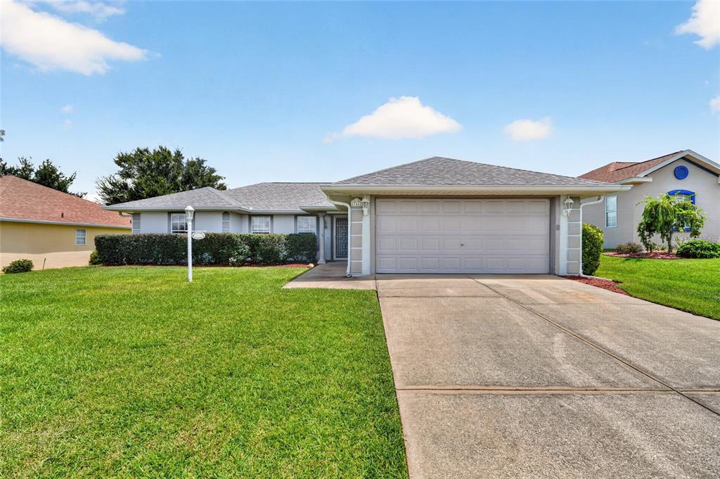 A single-story house with a gray shingled roof, light siding, and a two-car garage — 17461 SE 110TH COURT, SUMMERFIELD, FL