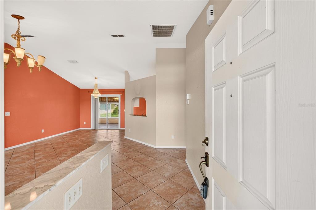 An entryway with tiled floors leads into a living area with an orange accent wall — 17461 SE 110TH COURT, SUMMERFIELD, FL