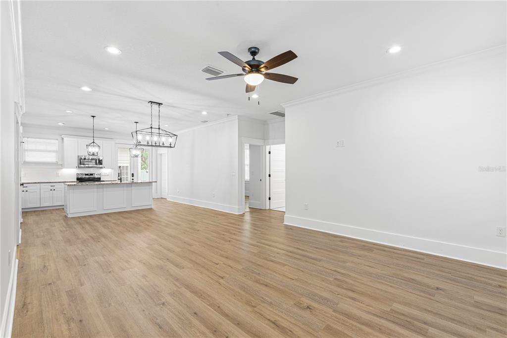 An open-concept living area with light wood flooring, a ceiling fan, and a white kitchen — 3923 W GRAY STREET, TAMPA, FL