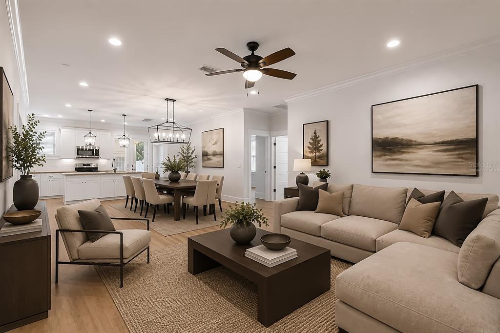A living room and dining area with neutral furniture, hardwood floors, and a kitchen background — 3923 W GRAY STREET, TAMPA, FL