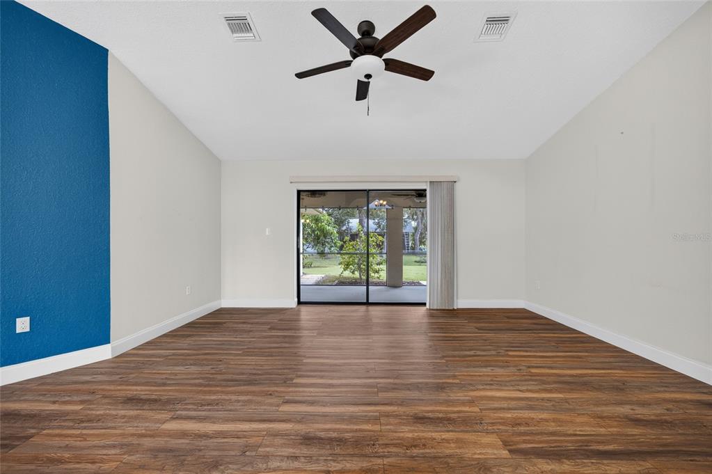 An empty living room features wood-look flooring, a blue accent wall, and sliding glass doors — 2058 LAKE VIEW BOULEVARD, PORT CHARLOTTE, FL
