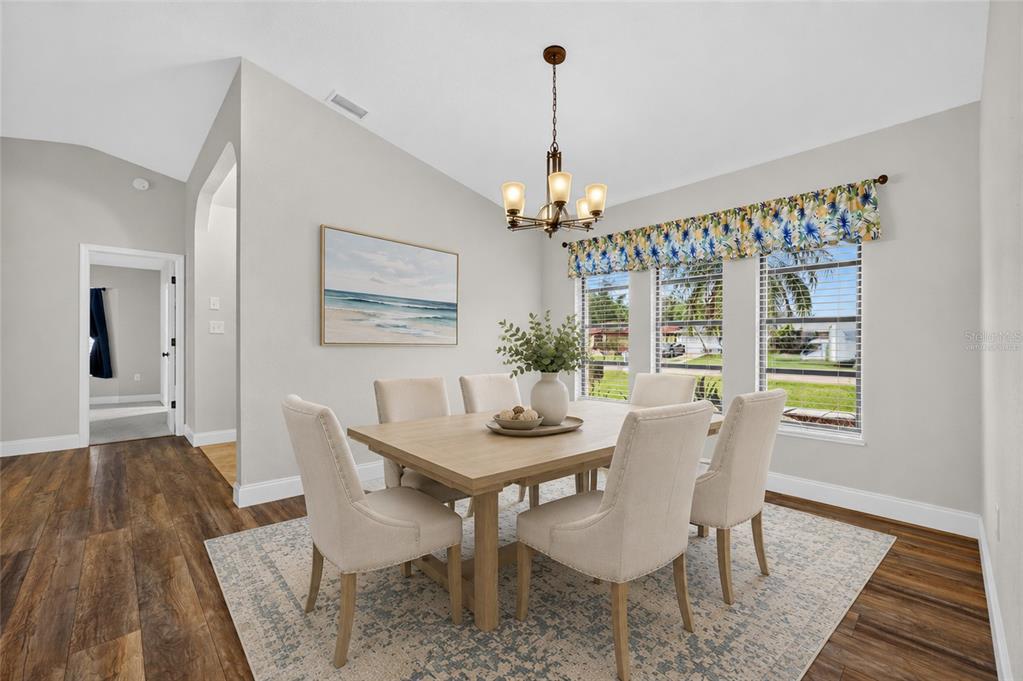 A dining room features a wooden table with six upholstered chairs on a patterned rug — 2058 LAKE VIEW BOULEVARD, PORT CHARLOTTE, FL