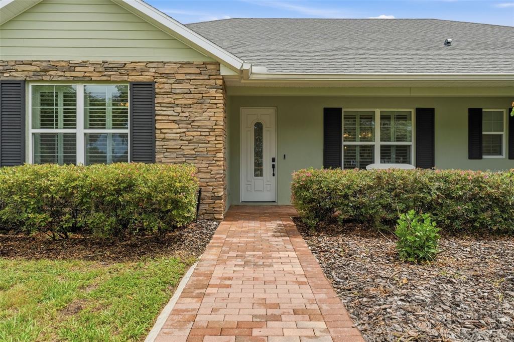 A brick walkway leads to the front entrance of a house with stone siding — 4526 CLAIRE ROSE COURT, MOUNT DORA, FL