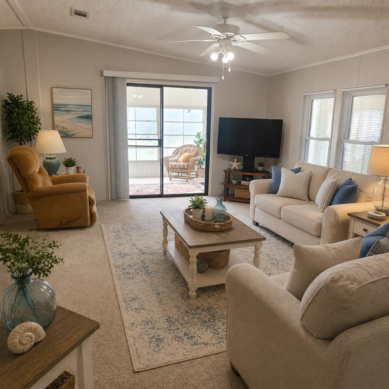 A sunroom features a red patterned rug, two wicker chairs, and windows overlooking a lake — 6114 GRAND OAKS DRIVE SE, WINTER HAVEN, FL