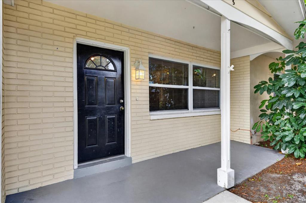 A black front door and a window are set into a light-colored brick exterior wall — 615 5TH AVENUE N, SAFETY HARBOR, FL