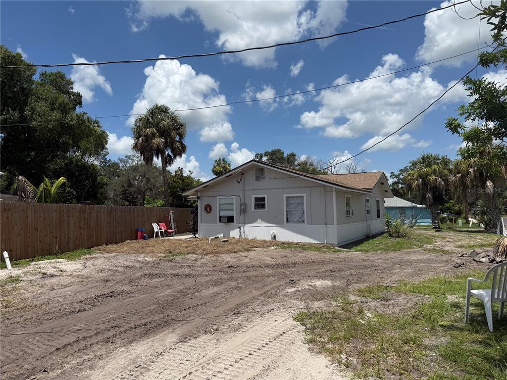 A single-story house with light-colored siding stands on a dirt lot with a wooden fence — 326 E WHIDDEN STREET, ARCADIA, FL