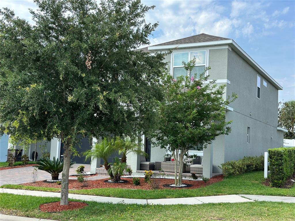 A two-story house with a gray exterior, a front porch, and mature landscaping — 2403 BISCOTTO CIRCLE, DAVENPORT, FL
