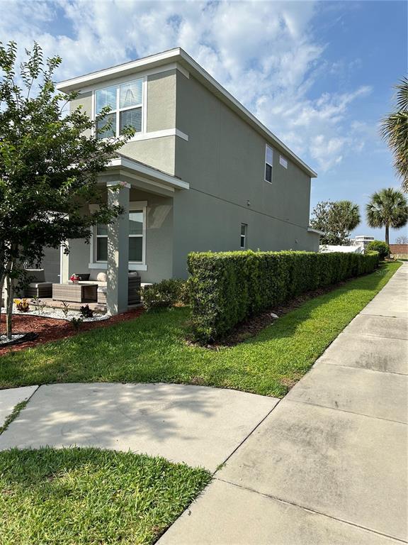 A two-story house with a covered front porch and a tall hedge along the side — 2403 BISCOTTO CIRCLE, DAVENPORT, FL