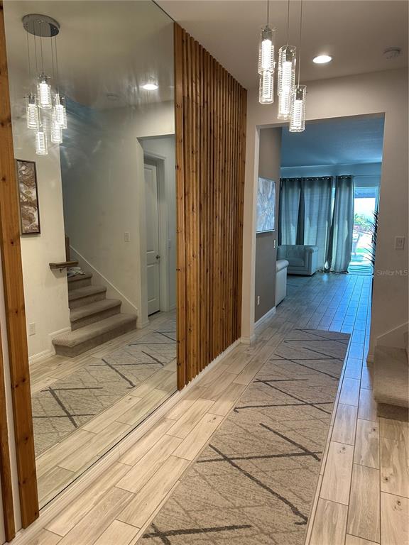 A hallway features light wood-look tile flooring, a large wall mirror, and vertical wood slats — 2403 BISCOTTO CIRCLE, DAVENPORT, FL