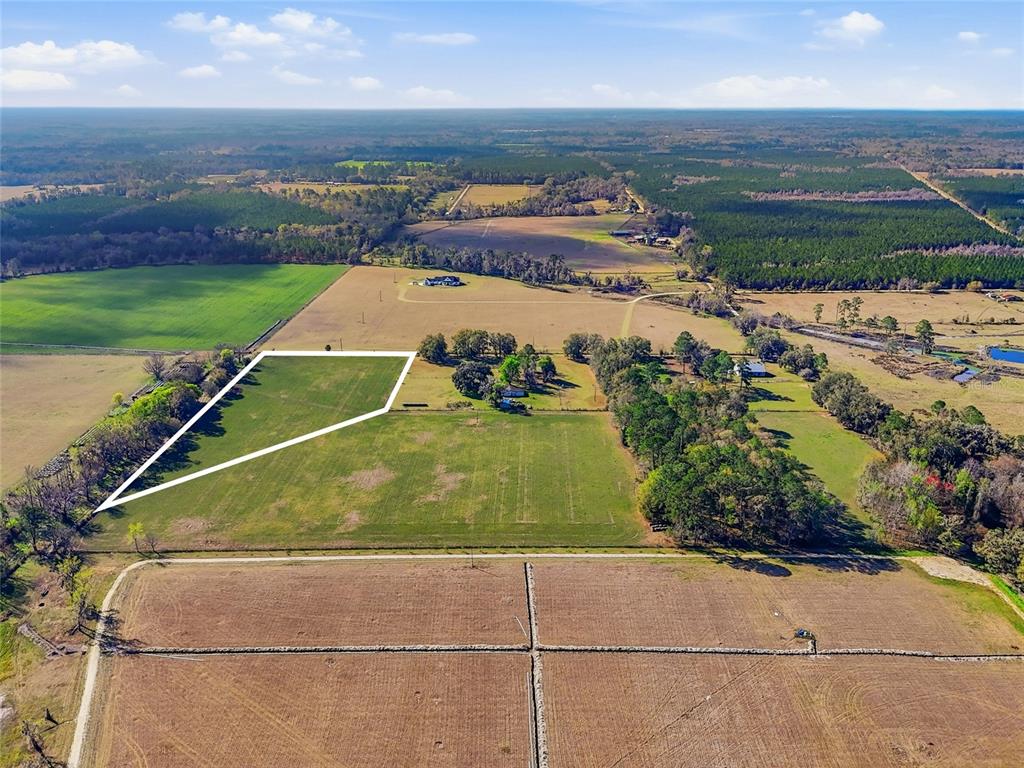 An aerial view shows a large, open grassy field outlined in white within a rural landscape — NW COUNTY RD 239, ALACHUA, FL