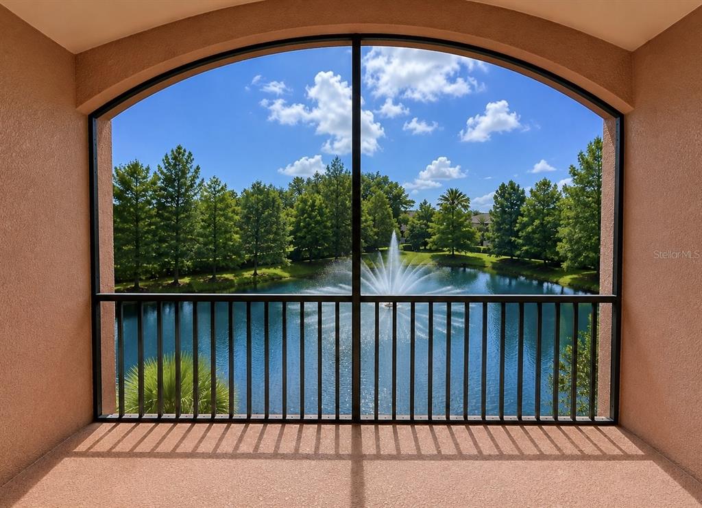 A screened-in balcony overlooks a pond with a fountain and surrounding trees — 1357 VENEZIA COURT UNIT 303, DAVENPORT, FL