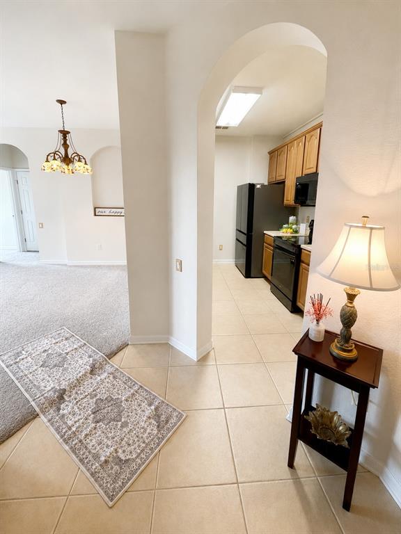 A tiled entryway leads to a kitchen with wood cabinets and a carpeted living area — 1357 VENEZIA COURT UNIT 303, DAVENPORT, FL