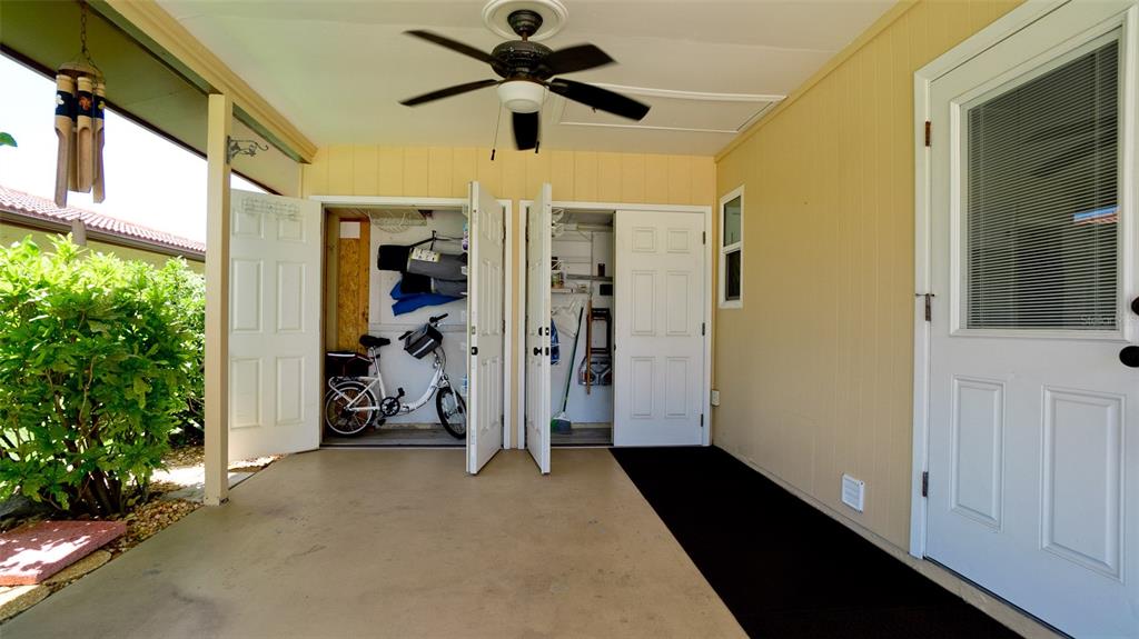 A covered patio features a ceiling fan, two storage closets with open doors, and a white door — 3305 NOTRE DAME PLACE, BRADENTON, FL