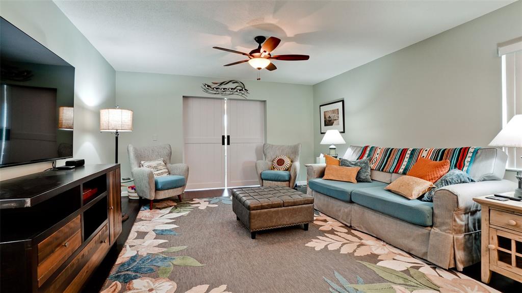 A living room features a sofa, two armchairs, an ottoman, and a large television — 3305 NOTRE DAME PLACE, BRADENTON, FL