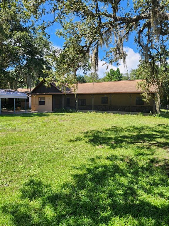 A single-story house with a screened-in porch and a detached metal carport on a lawn — 7095 W GREENWOOD LANE, CRYSTAL RIVER, FL