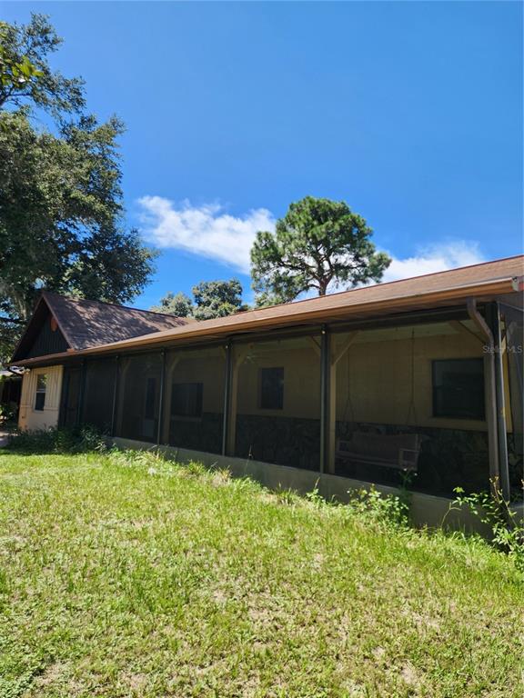 The exterior of a house features a screened-in porch, tan siding, and a sun decoration — 7095 W GREENWOOD LANE, CRYSTAL RIVER, FL