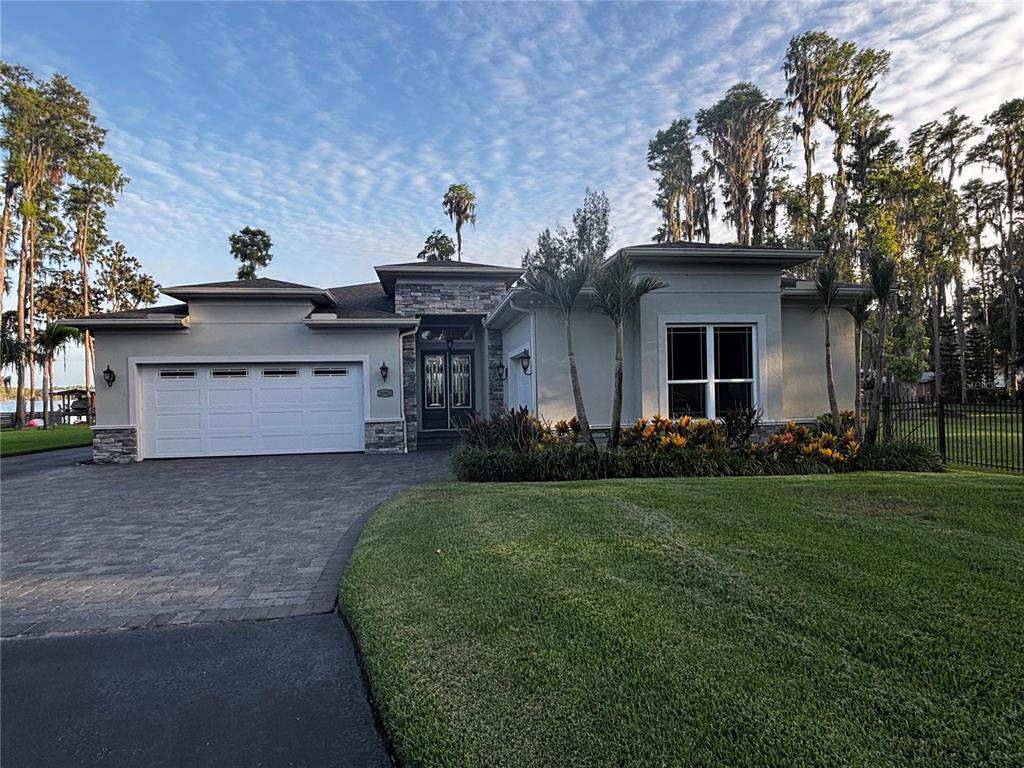 A single-story house with a stone-accented entrance, white garage, and palm trees in the front yard — 20902 RAGAN LANE, LAND O LAKES, FL