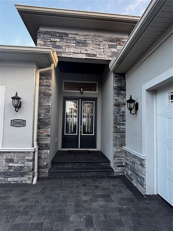 A front entryway features a stone facade, double doors, and a paved walkway — 20902 RAGAN LANE, LAND O LAKES, FL