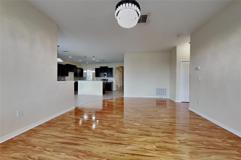A dining area with wood-look flooring leads to an open kitchen with dark cabinetry — 9609 ROYAL FERN COURT, TAMPA, FL