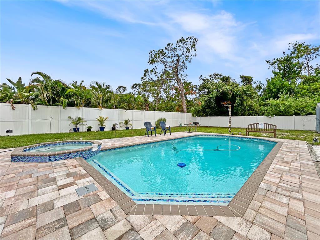 A backyard features a swimming pool with an attached hot tub and a paver patio — 2501 32ND AVENUE W, BRADENTON, FL