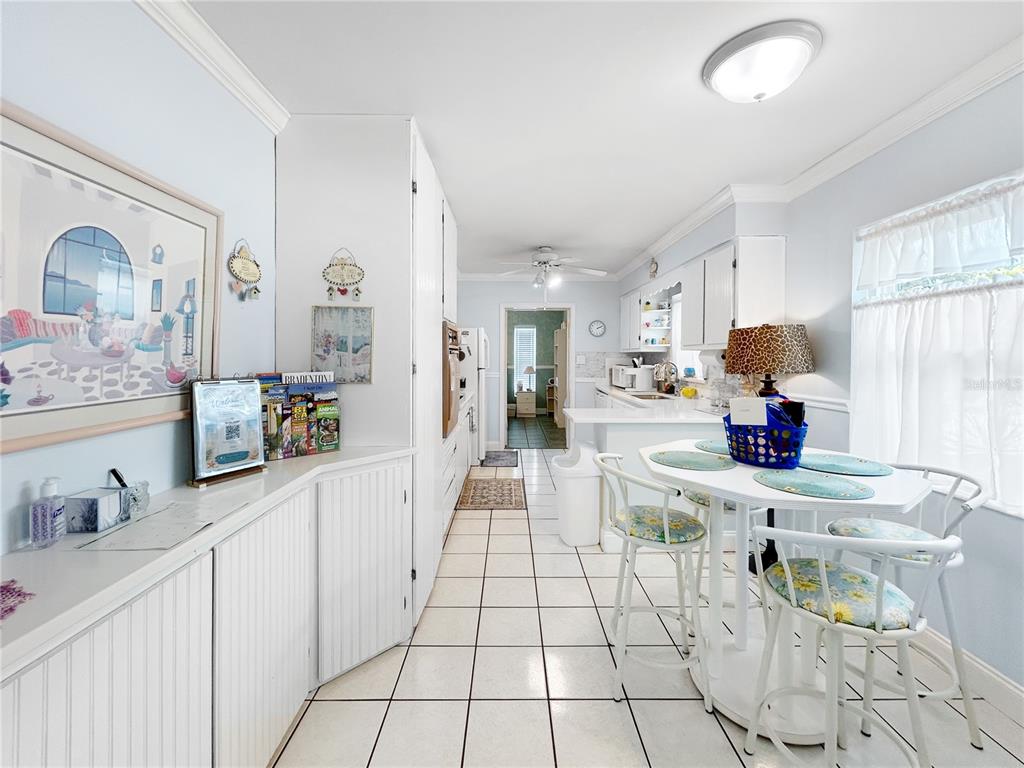 A kitchen features white cabinetry, tile flooring, a small dining table, and a ceiling fan — 2501 32ND AVENUE W, BRADENTON, FL