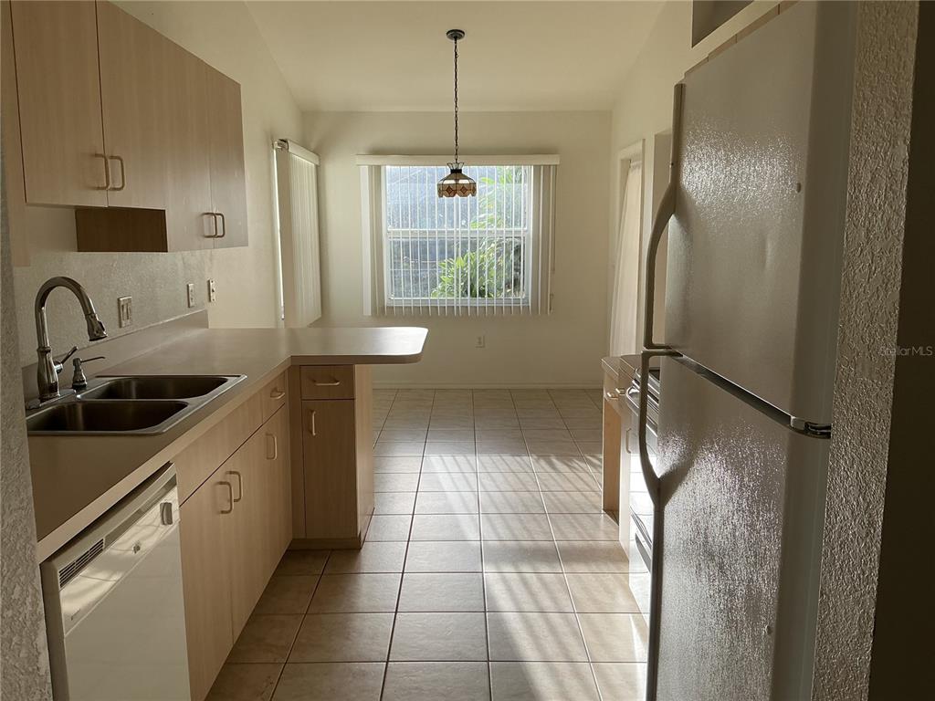 This kitchen features light wood cabinets, white appliances, a double sink, and tiled flooring — 2700 S BISCAYNE DRIVE, NORTH PORT, FL