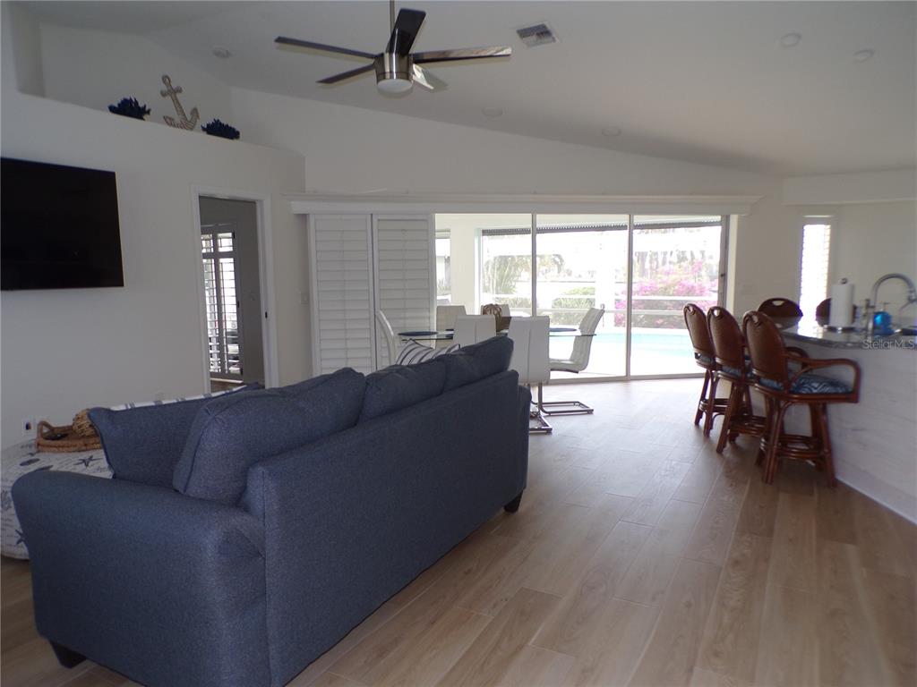 A living room with a blue sofa, dining area, and kitchen island overlooks a pool — 3804 TURTLE DOVE BOULEVARD, PUNTA GORDA, FL
