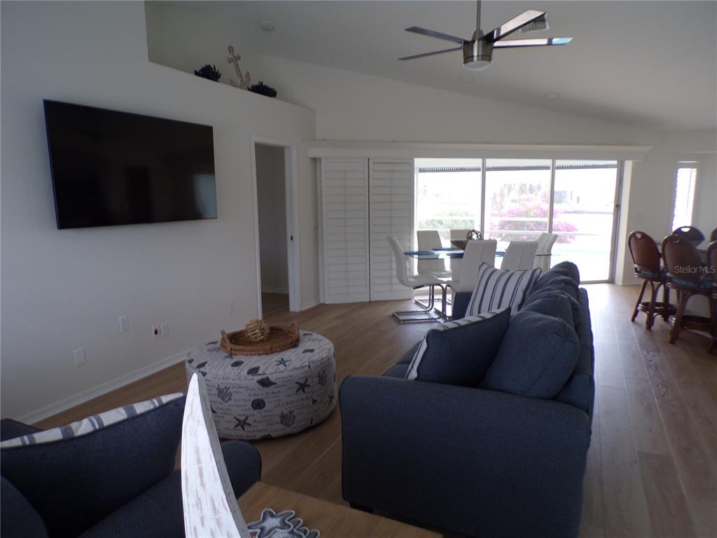 A living room features a blue sofa, a patterned ottoman, and a dining area nearby — 3804 TURTLE DOVE BOULEVARD, PUNTA GORDA, FL
