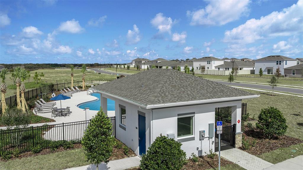 An aerial view shows a community pool and clubhouse with a blue door and landscaping — 7760 CLOUDBURST DRIVE, GROVELAND, FL