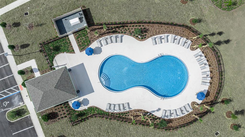 An aerial view shows a figure-eight swimming pool surrounded by lounge chairs and a pavilion — 7760 CLOUDBURST DRIVE, GROVELAND, FL