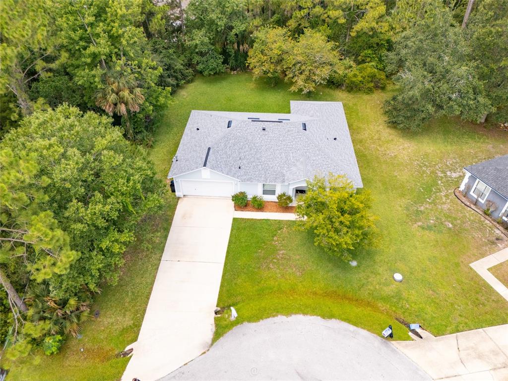 An aerial view shows a single-story house with a gray roof and concrete driveway — 19 BURREL PLACE, PALM COAST, FL