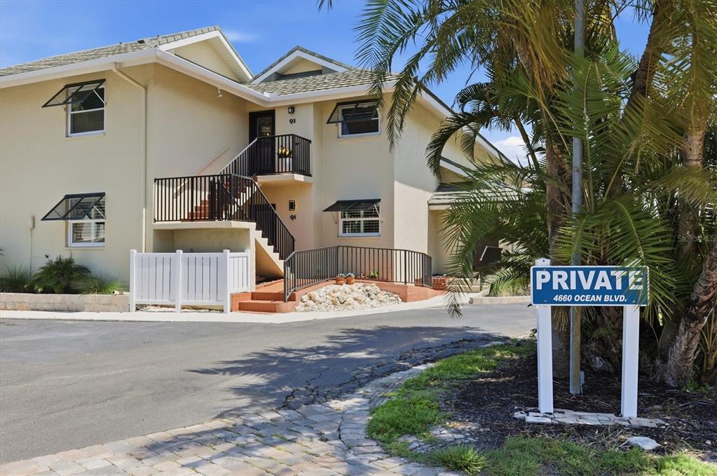 An aerial view shows a coastal residential complex with palm trees, parking, and turquoise water — 4660 OCEAN BOULEVARD UNIT Q2, SARASOTA, FL