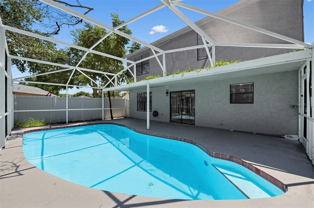 A swimming pool with a brick border sits on a patio enclosed by a screen cage — 4226 CLOVERLEAF PLACE, CASSELBERRY, FL