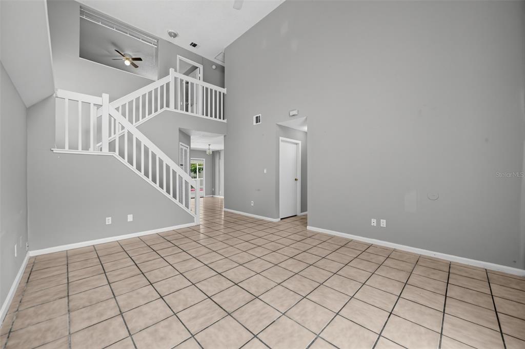 An empty room with light gray walls, tile flooring, and a white staircase — 4226 CLOVERLEAF PLACE, CASSELBERRY, FL