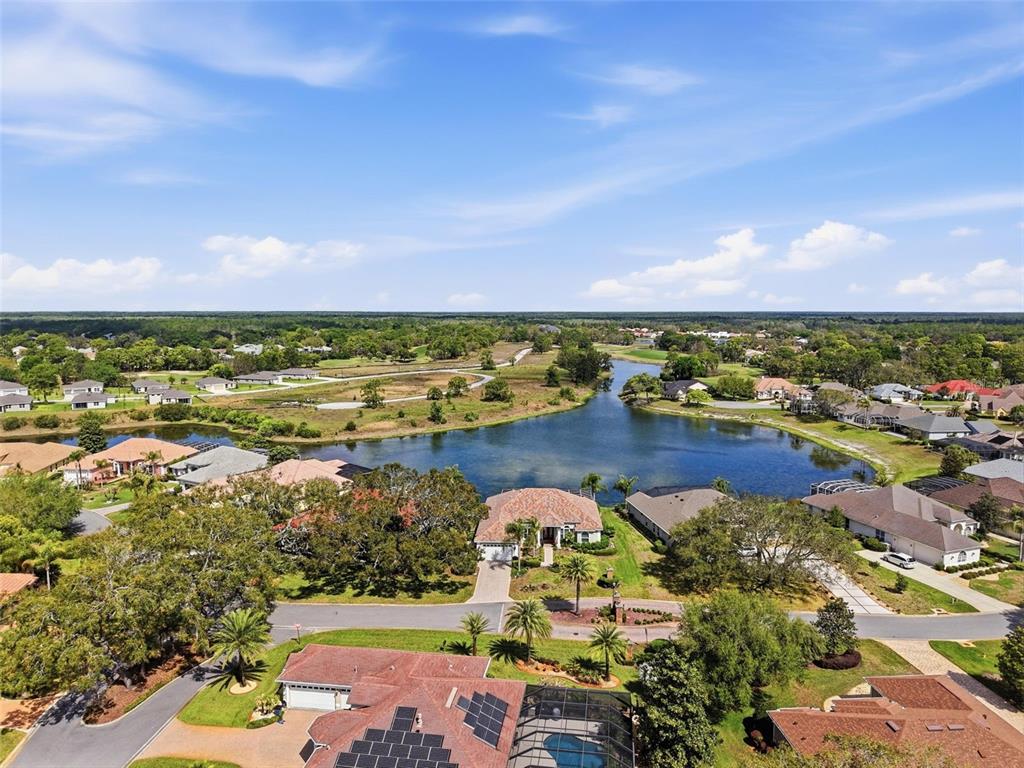 An aerial view shows a suburban neighborhood with houses surrounding a central lake — 9203 LAKE CYPRESS LOOP, WEEKI WACHEE, FL