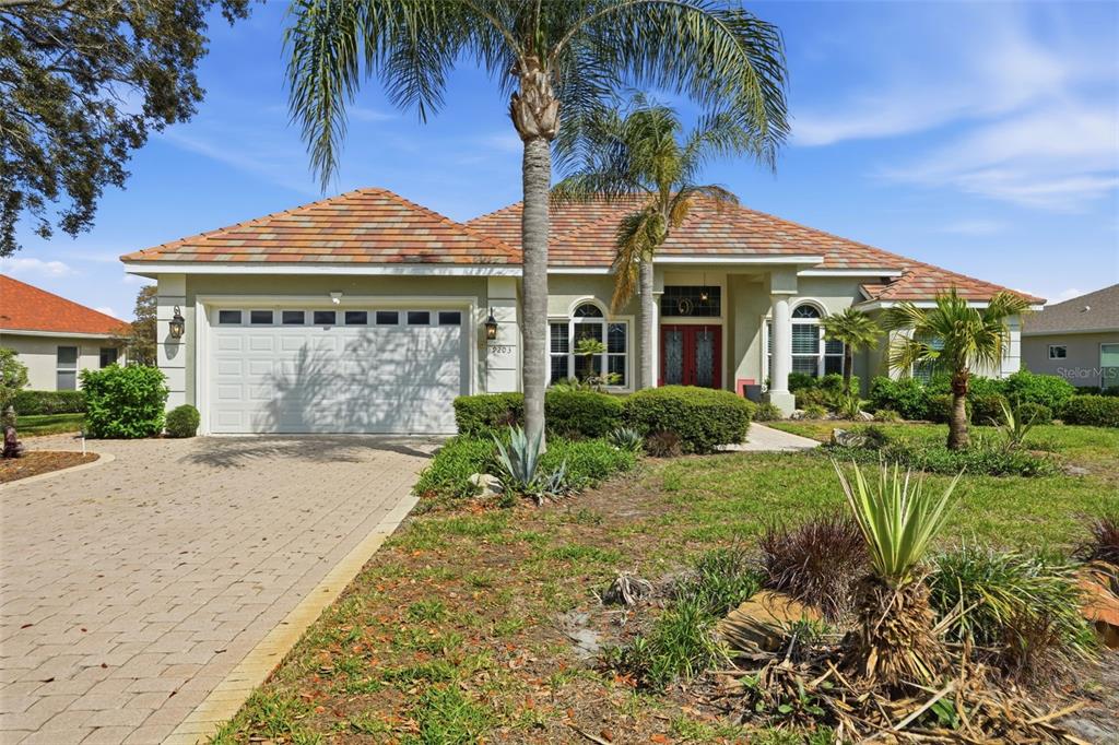 A single-story house with a tiled roof, a paved driveway, and palm trees in front — 9203 LAKE CYPRESS LOOP, WEEKI WACHEE, FL