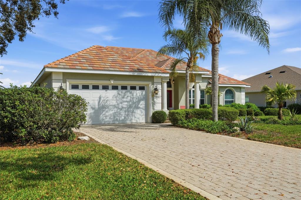 A single-story house with a tiled roof, white garage door, and a paved driveway — 9203 LAKE CYPRESS LOOP, WEEKI WACHEE, FL